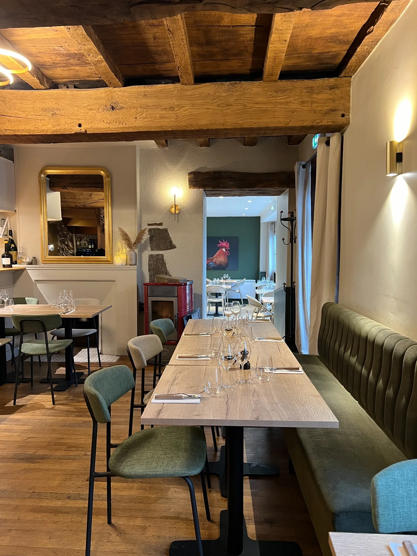 Tables dressées, banquette verte et poutres en bois dans la salle de Cocorico